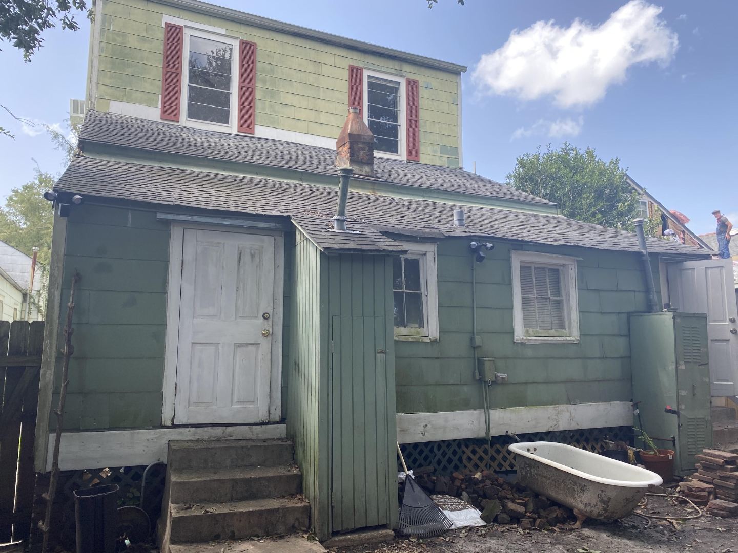 Before — deteriorated rear exterior with debris and worn siding