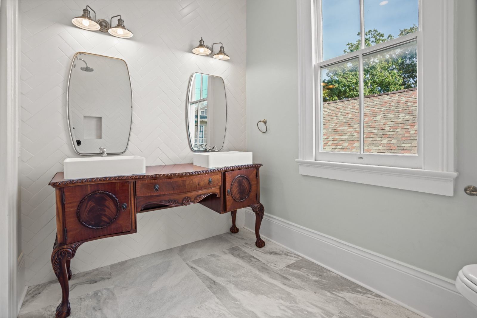 Antique carved sideboard repurposed as double vanity with vessel sinks and herringbone wall tile