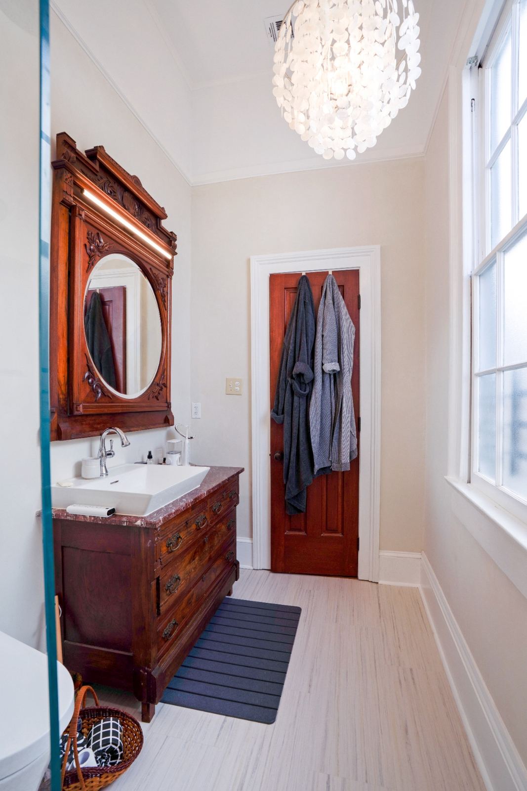 Master bath with capiz chandelier and antique carved vanity