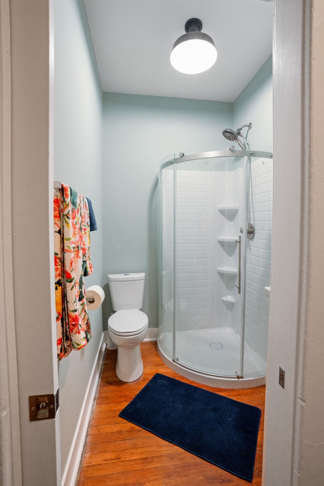 Corner glass shower with curved door and pedestal sink