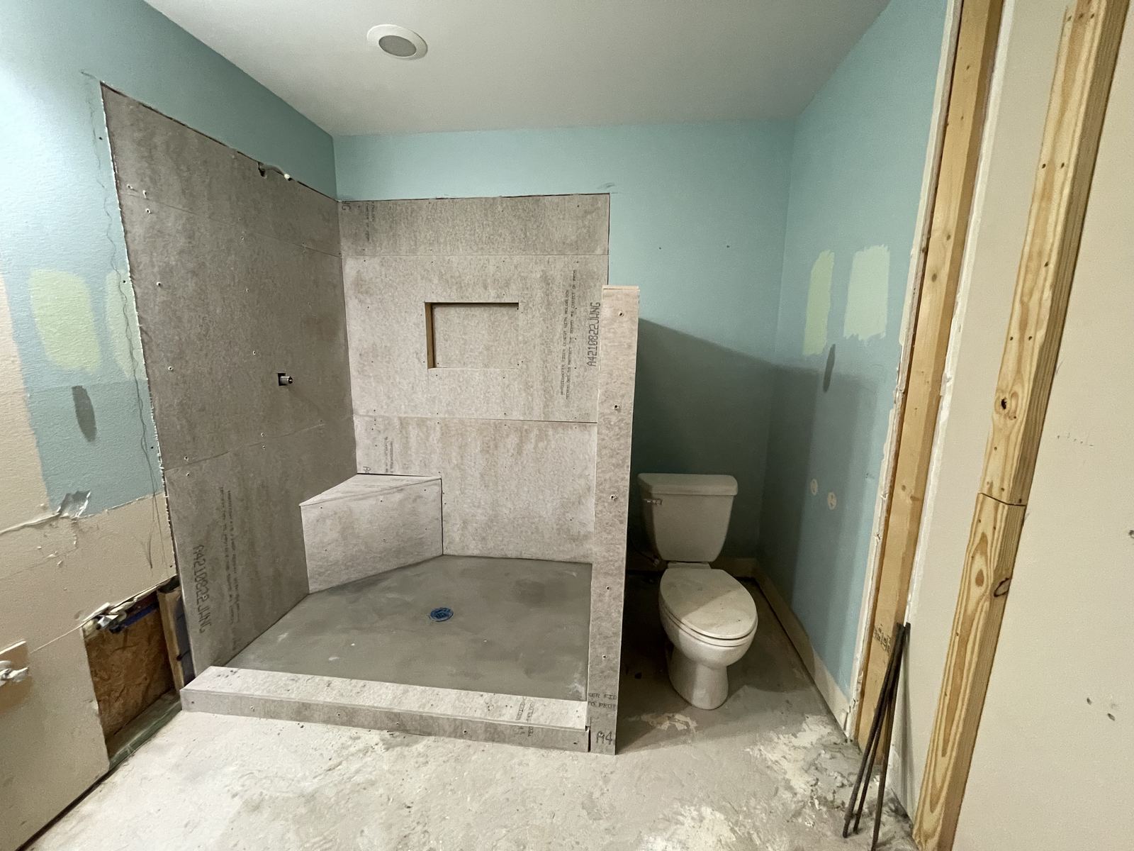 Large format marble tile walk-in shower with black and white hex floor, bench and glass shelf