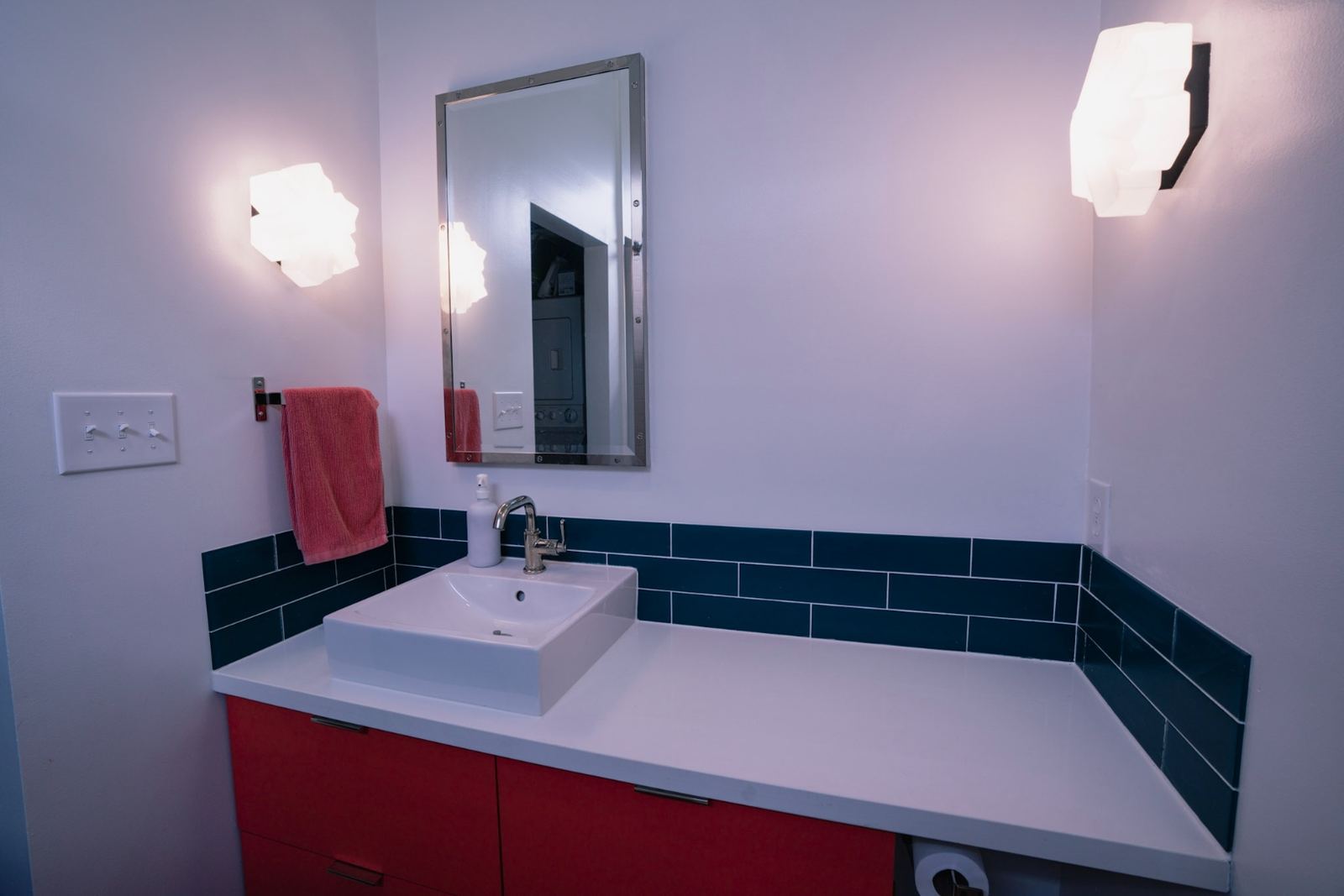 Modern bathroom with navy tile strip backsplash, red floating cabinet and vessel sink