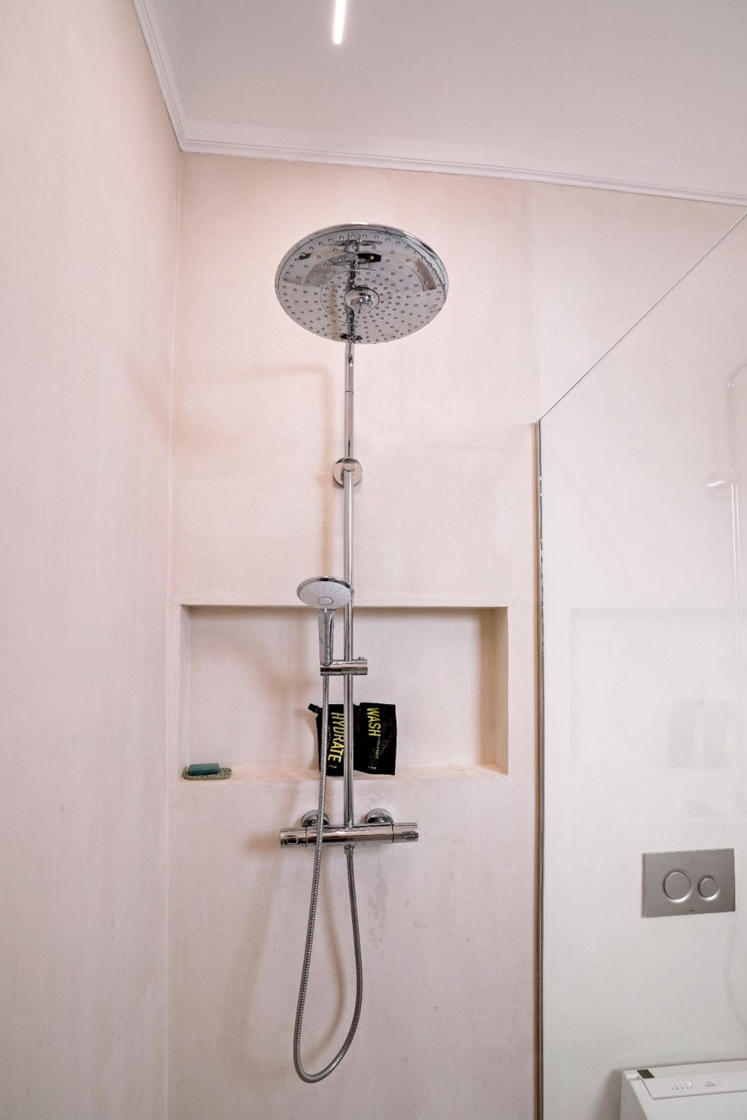 Plaster shower interior with rainfall showerhead detail