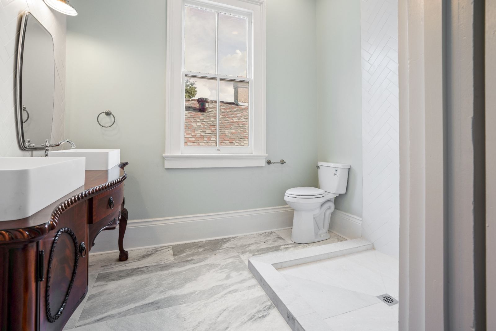 Antique ornate vanity with marble top in sage green bathroom