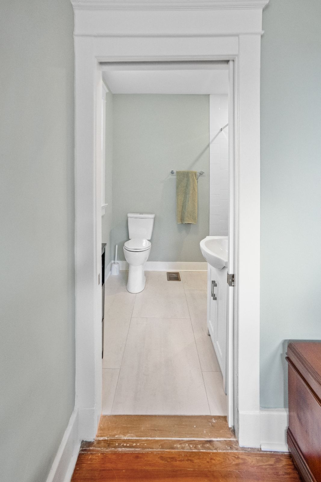 Sage green bath with round black mirror and white herringbone shower