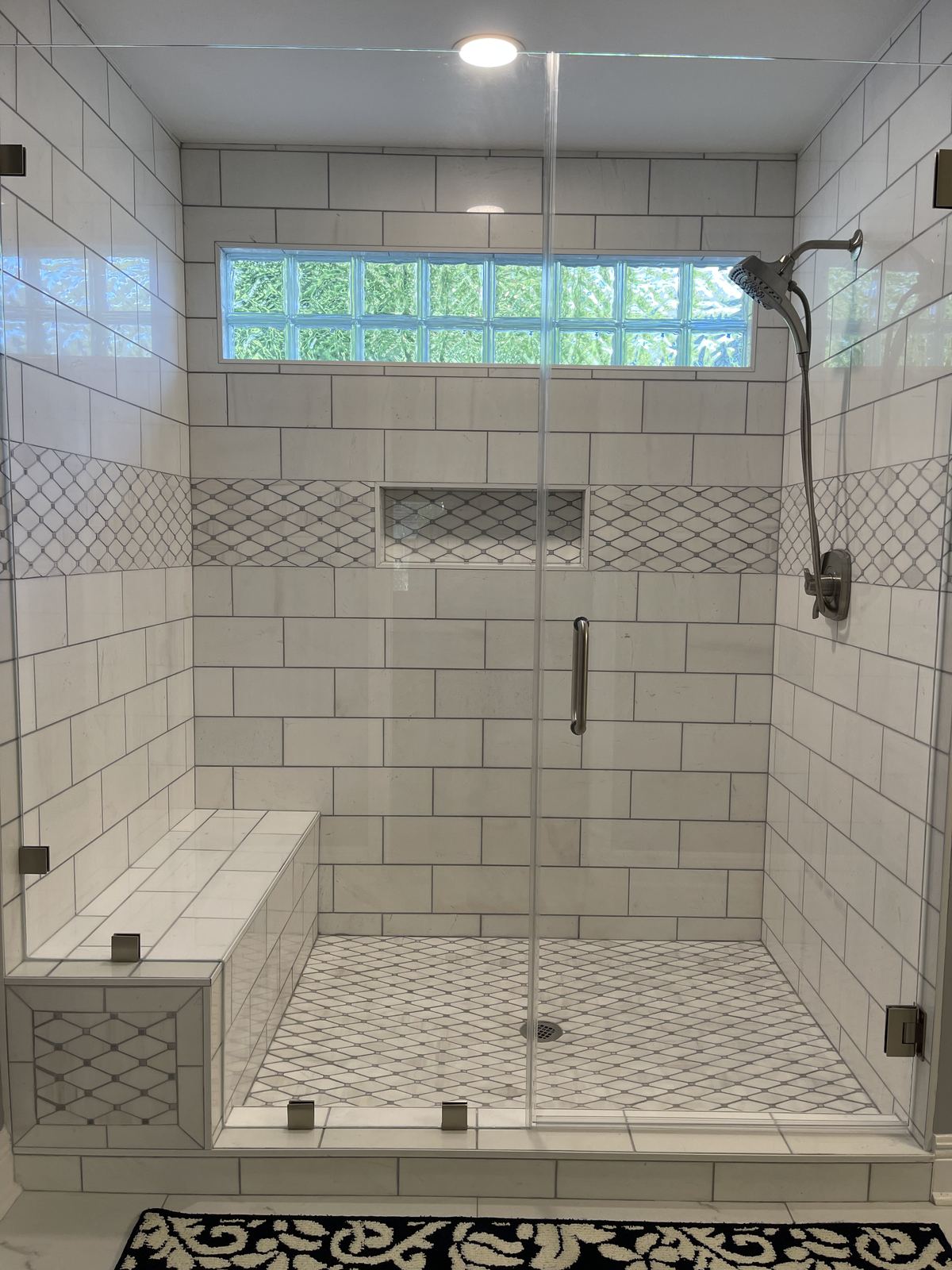 Subway tile walk-in shower detail with mosaic accents