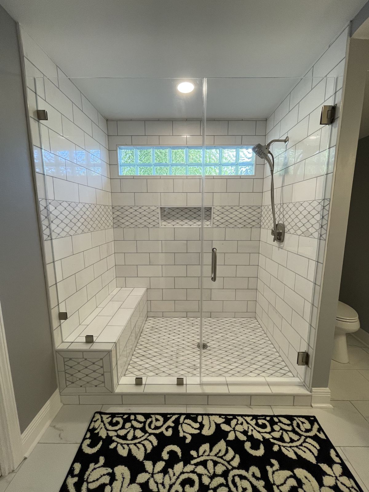 Custom walk-in shower with subway tile, glass block window and built-in bench