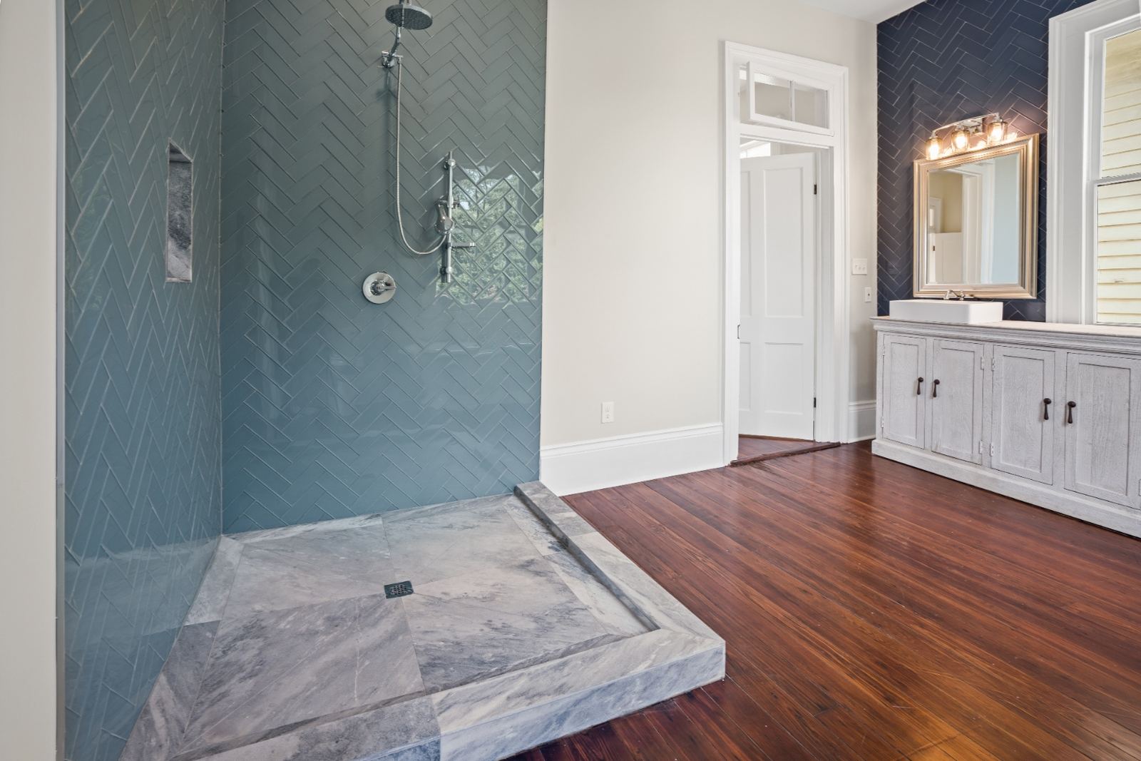 Teal herringbone shower detail with marble surround