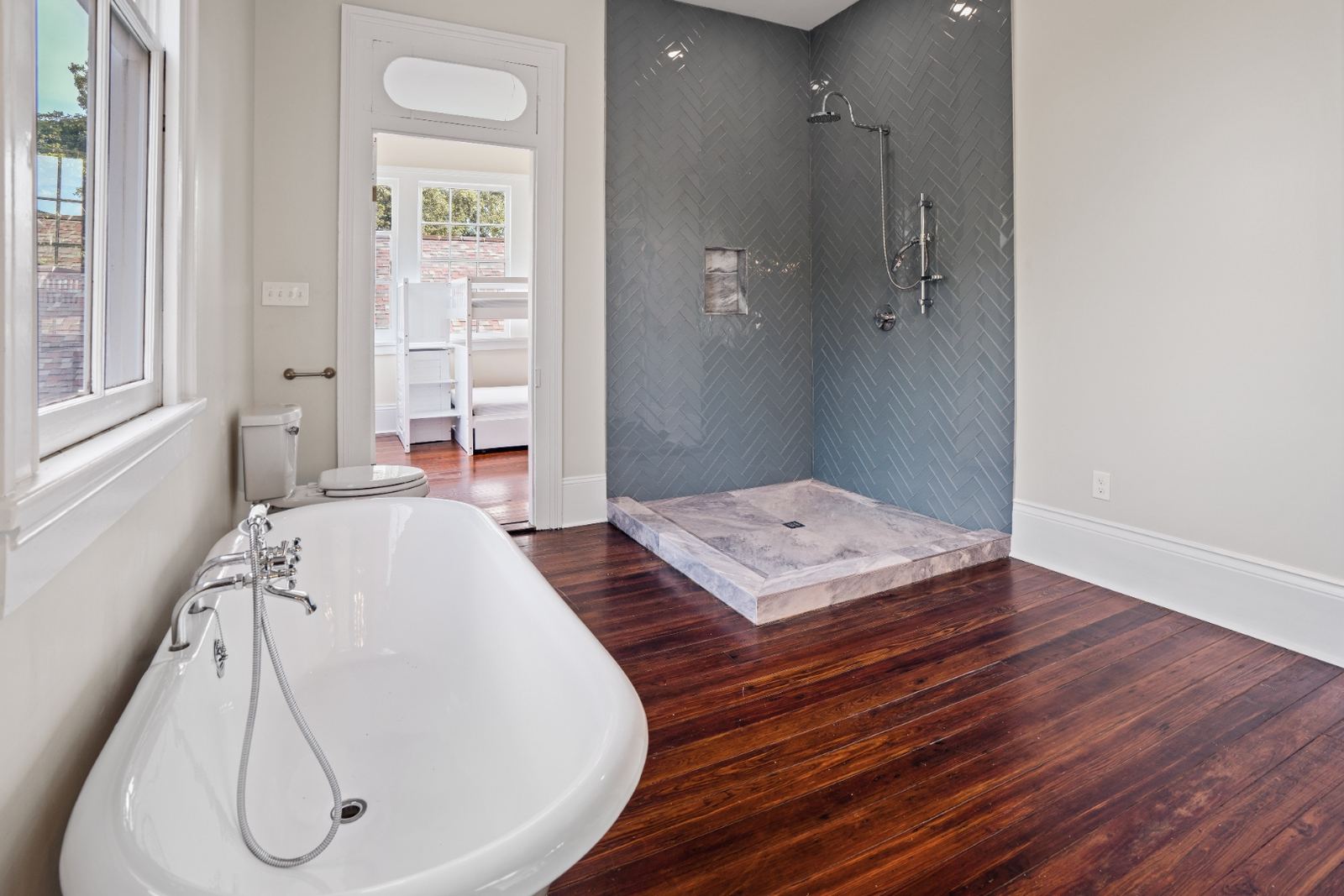 Teal herringbone shower with marble base and freestanding tub