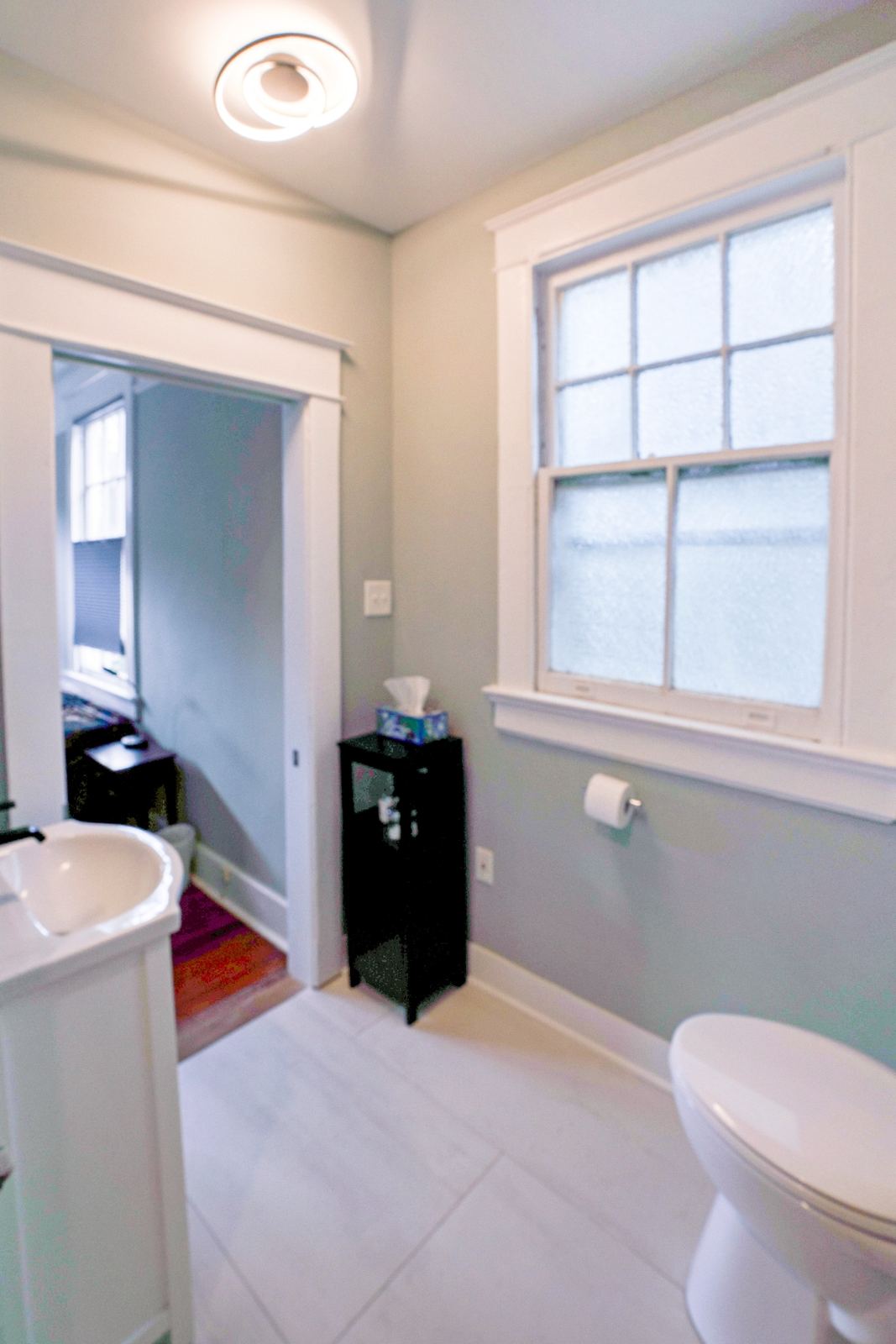 Clean white bathroom with pedestal sink and large window