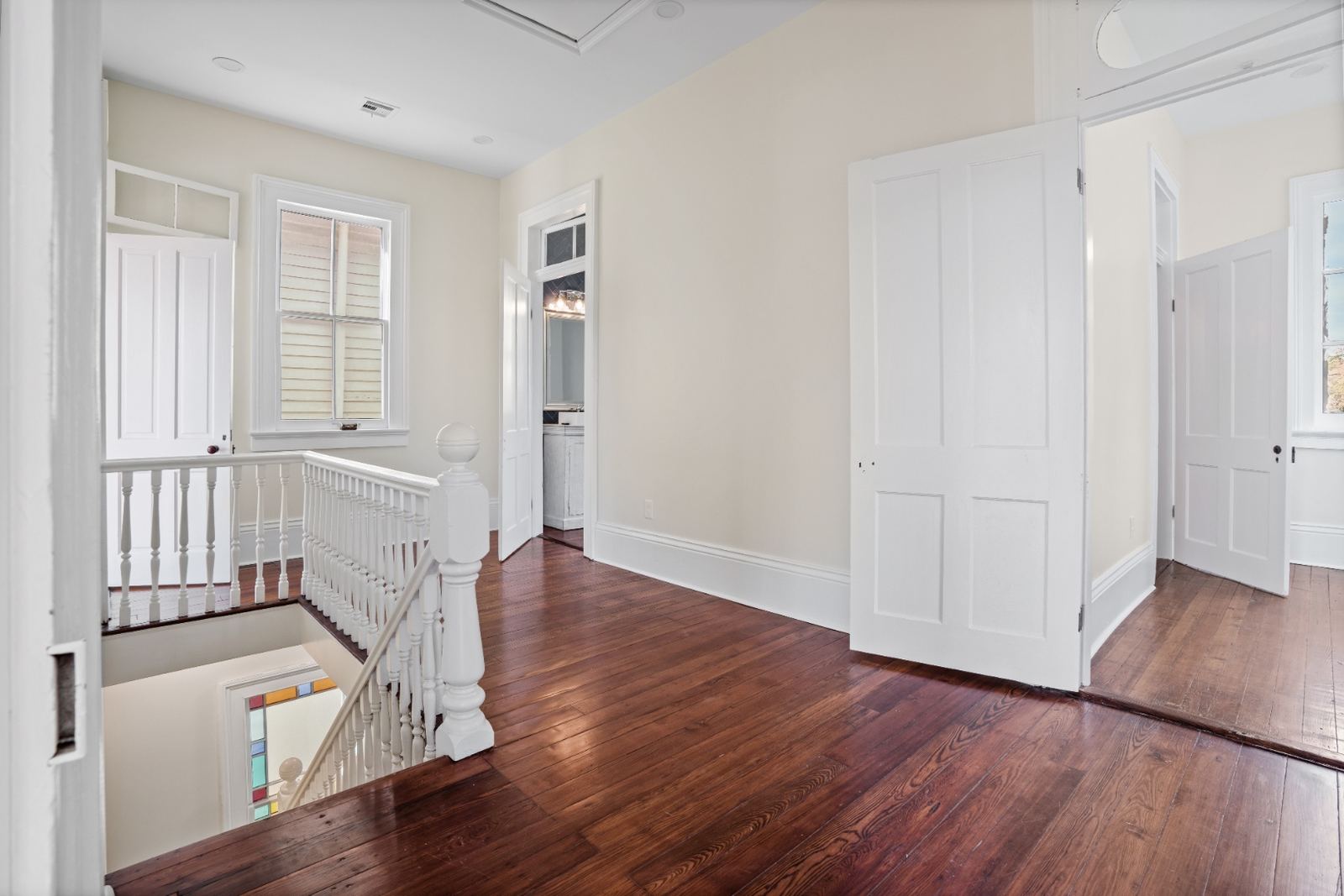 Upper hallway landing with original balusters and stained glass