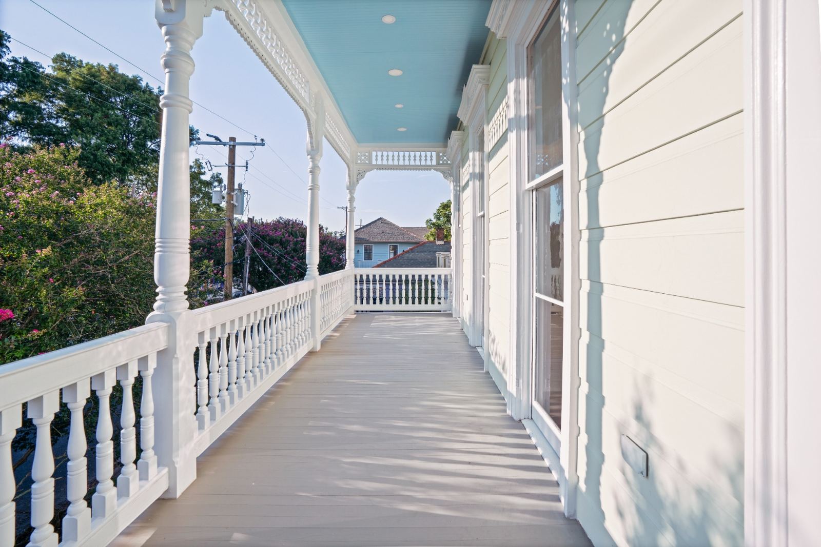 Restored upper porch with haint blue ceiling and ornate millwork