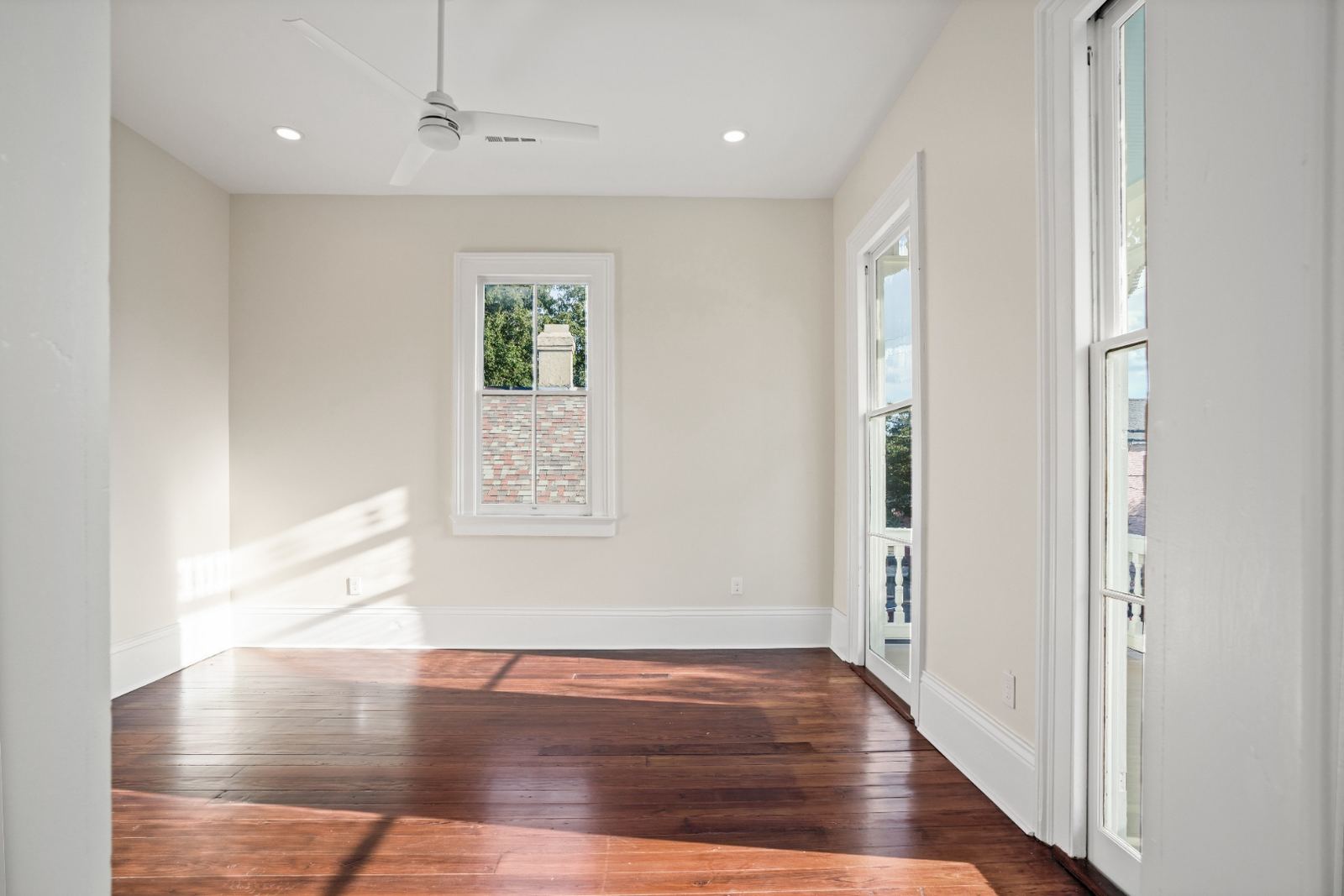 Renovated bedroom with original hardwood floors and balcony access