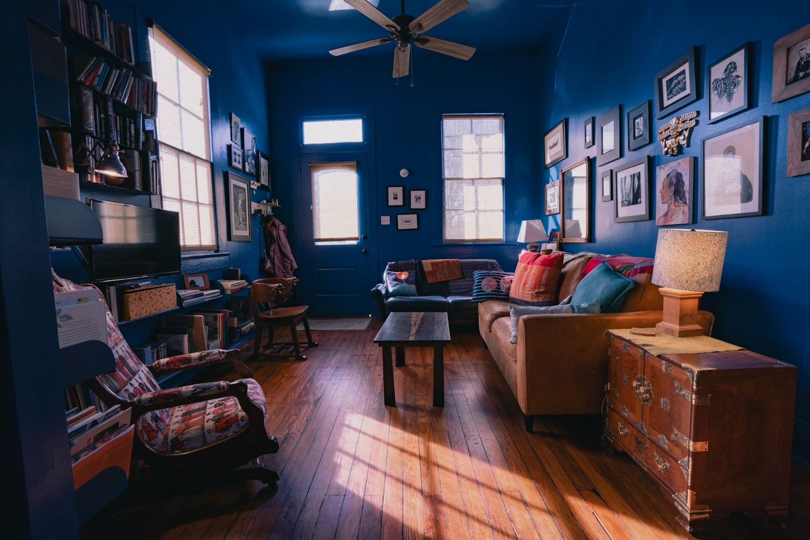 Royal blue living room with gallery wall, original hardwood floors and transom windows