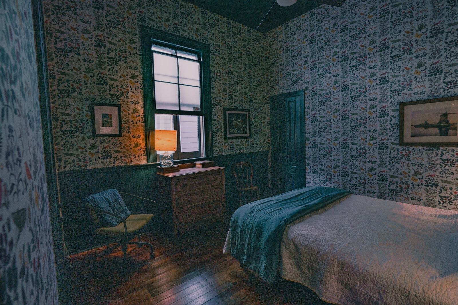 Historic shotgun bedroom with floor-to-ceiling botanical wallpaper and exposed brick chimney