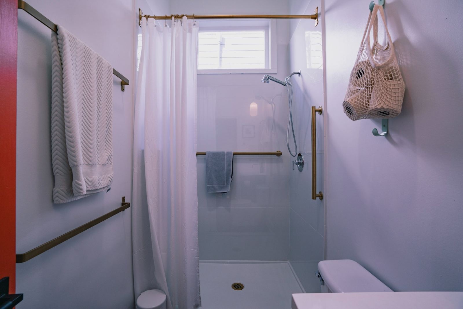 Red shotgun hallway with neon art sconce and view through to botanical bedroom