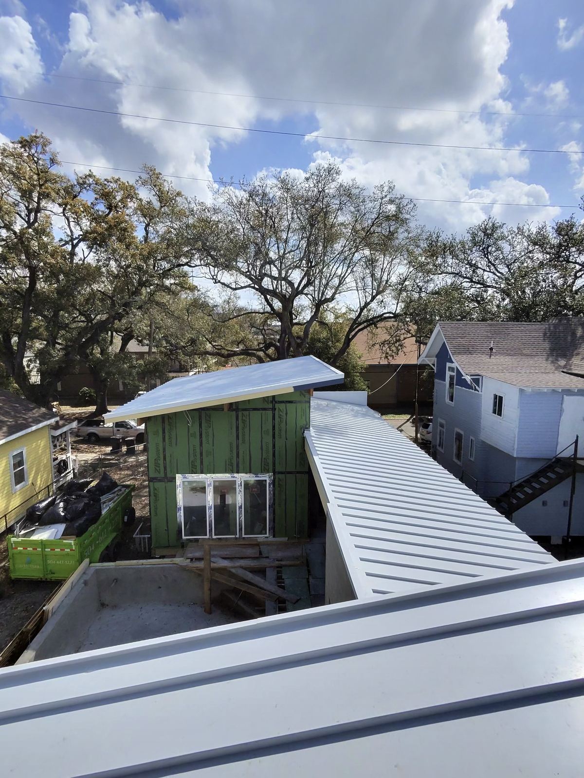 Rooftop aerial view of modern addition with standing seam metal roof and live oak canopy