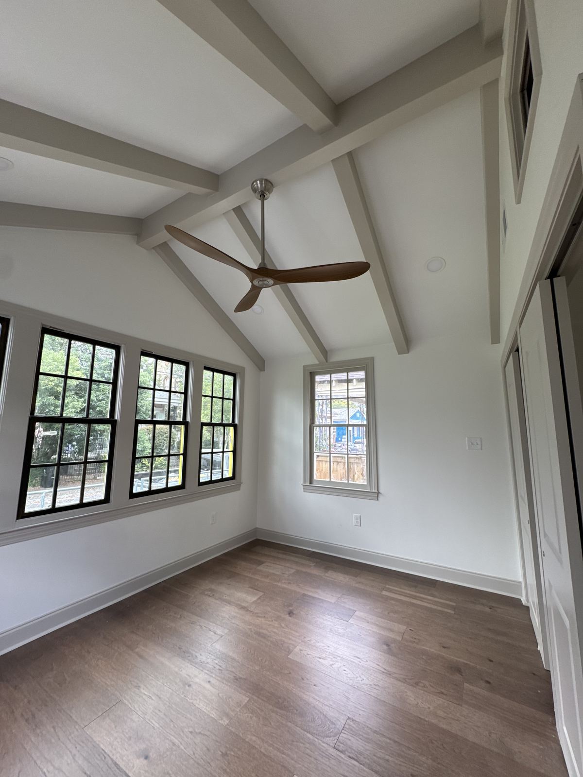 Master bedroom with vaulted beamed ceiling, black casement windows and hardwood floors
