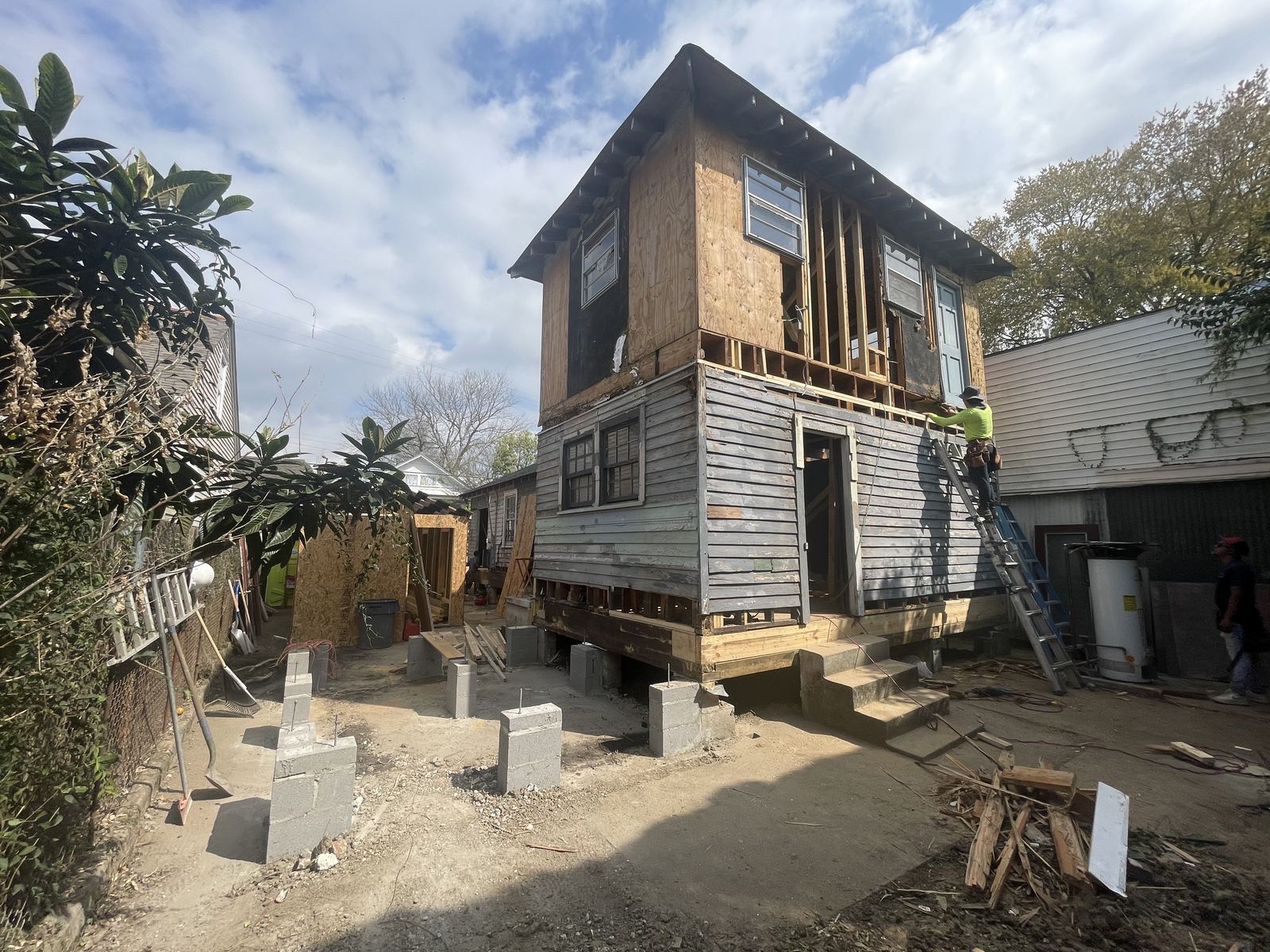 New construction home with ZIP system sheathing and Green Terra Construction banner under live oak
